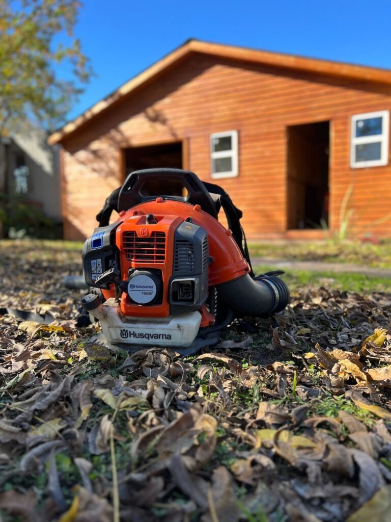 Leaf blower in focus of photo with leaves surrounding it