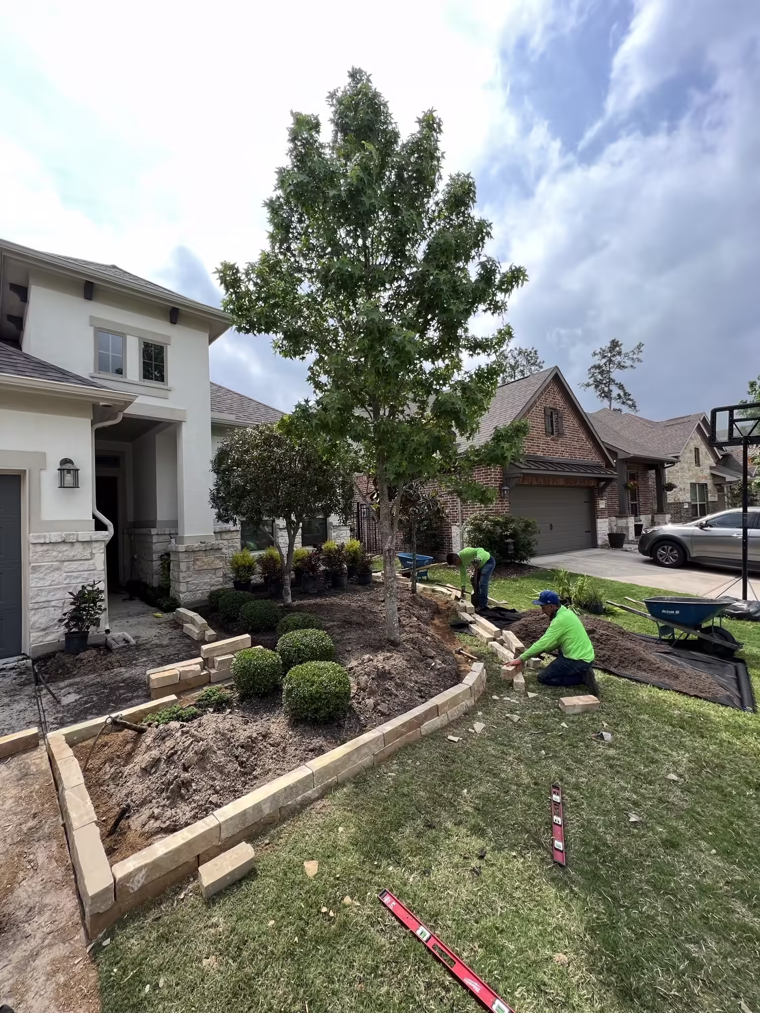 Two professional gardeners tending to a suburban Houston front garden, expertly providing lawn care and landscaping services to enhance curb appeal.