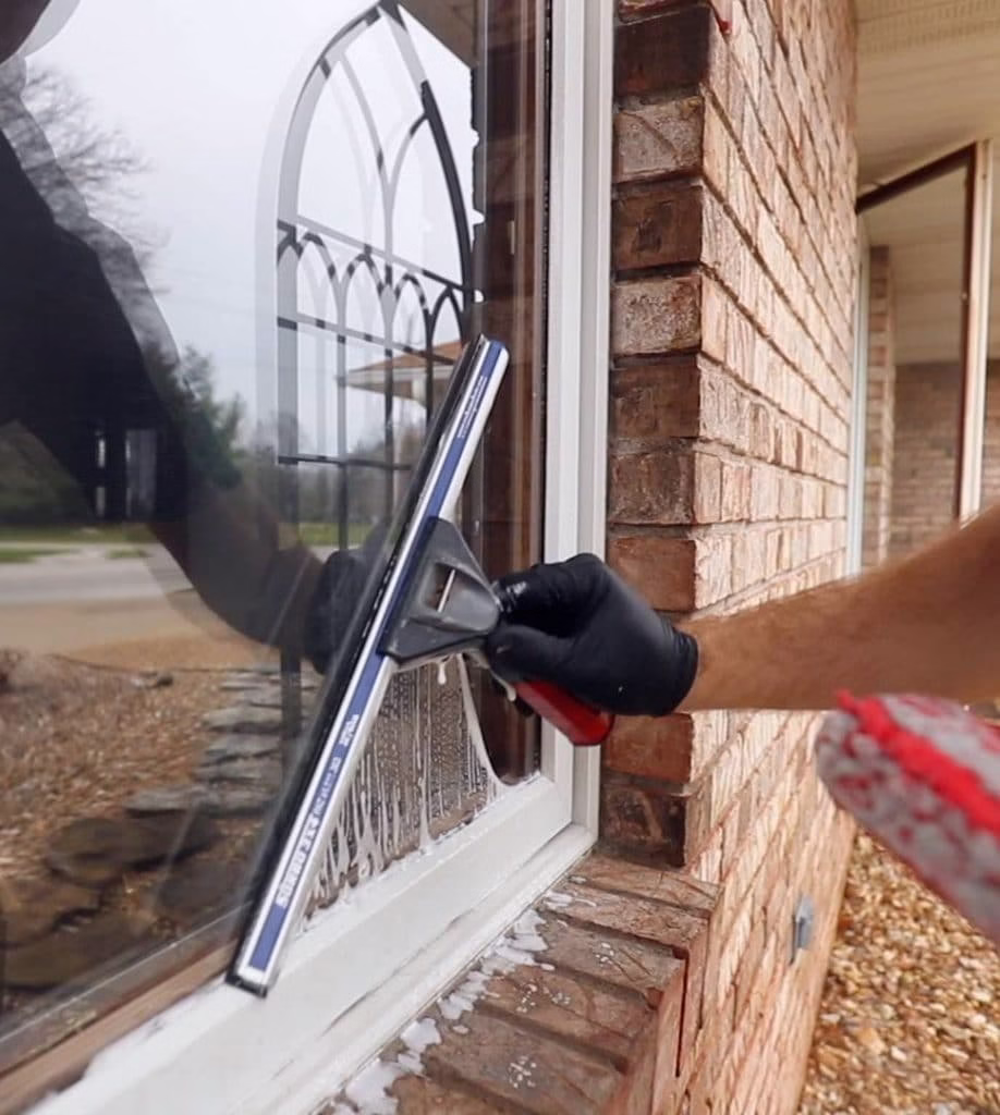 Man using squeegee on window of home